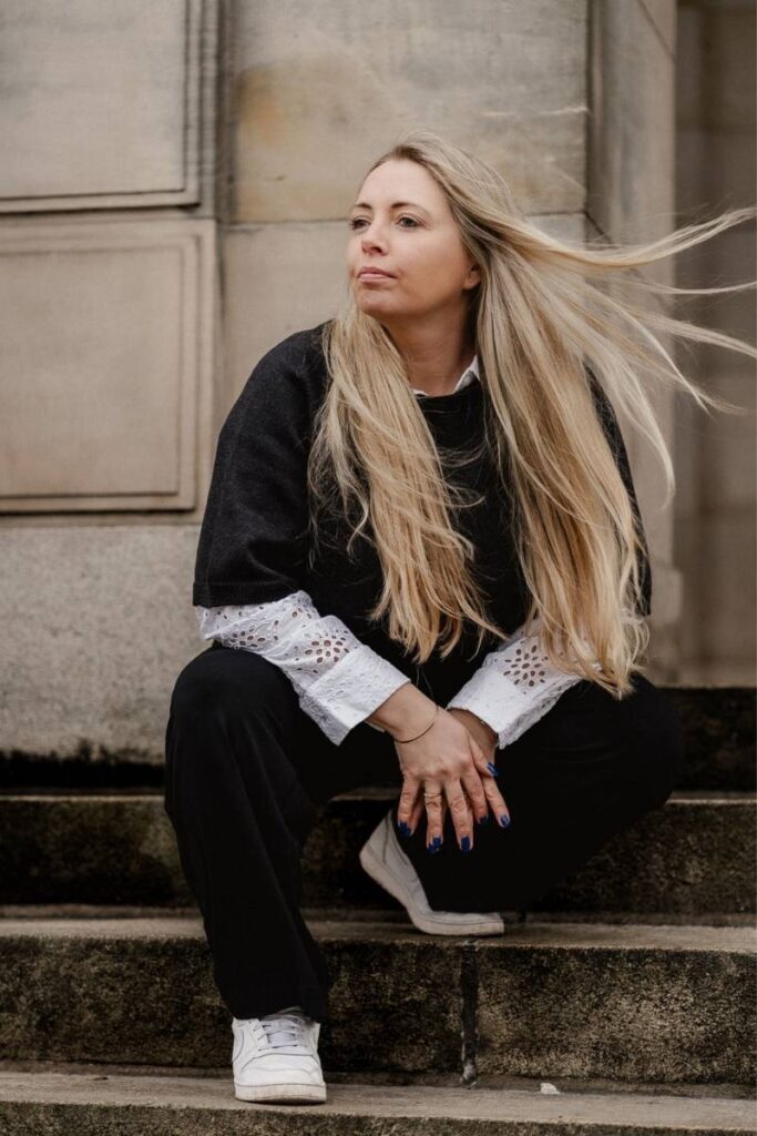 Blonde Frau sitzt auf Treppe im Portrait